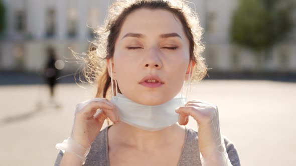 Happy Hispanic Girl Walking Outdoor While Taking Off Her Protective Face Mask and Looking at Camera alt