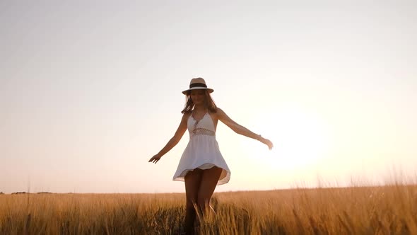 Happy Free Young Woman Dancing and Spinning Around in Slow Motion Across Field Touching Ears of alt