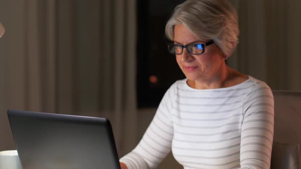 Happy Senior Woman with Laptop at Home in Evening alt