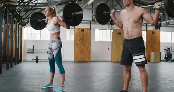 Side view of an athletic Caucasian man and woman squatting alt