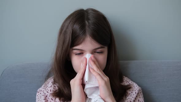 Little Girl a Teenager is Sick with the Flu Blows Her Nose in a Napkin