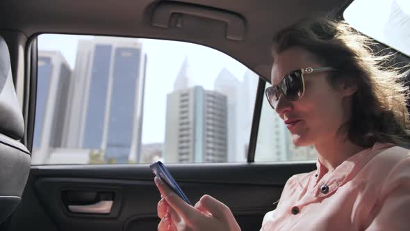 A Girl in a Moving Car is Typing a Message on the Phone alt