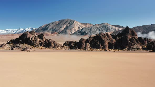 Flying Around the Dark Rocks on Bed of Ancient Dry Lake Bed, Cinematic Aerial alt