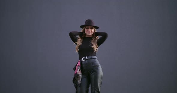Attractive Girl with a Hat on a Background of a Gray Wall Posing for the Camera alt