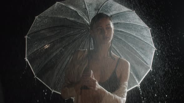 Hot Young Woman Standing Under the Rain and Twirls with an Umbrella alt