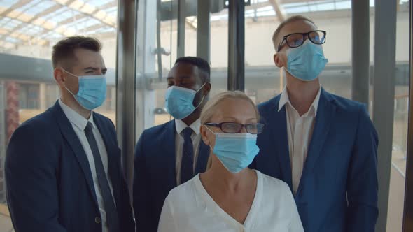 Diverse Businesspeople Wearing Safety Mask Using Elevator in Business Center alt