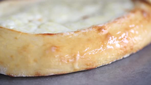 Baker greases khachapuri pie with butter, close up video