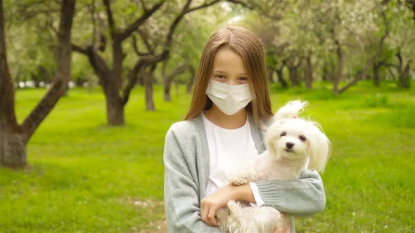 Little Girl with Dog Wearing Protective Medical Mask for Prevent Virus Outdoors in the Park