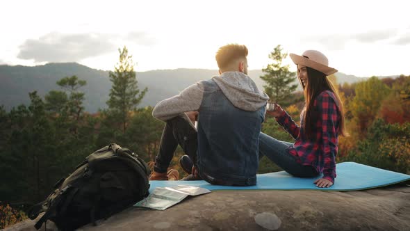 A Young Woman and a Man are Sitting on a Large Rock alt