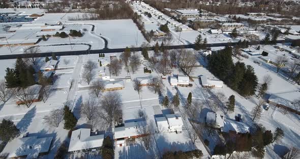 A slowlying forward snowy aerial flyover of a suburban Michigan residential neighborhood on a sunny alt