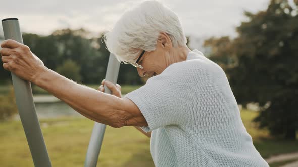 Old Woman Exercising in and Outdoor Gym, Slow Motion alt
