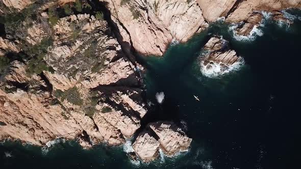 Flying above a man kayaking through mediterranean cliffs