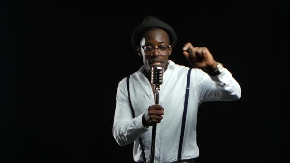 Singer Sings Into a Retro Microphone Spinning and Dancing Around Him. Black Background alt