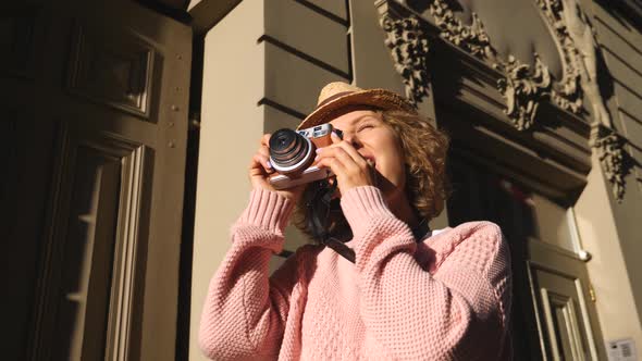 Woman Tourist Taking Photos With Vintage Camera While Sightseeing In City alt