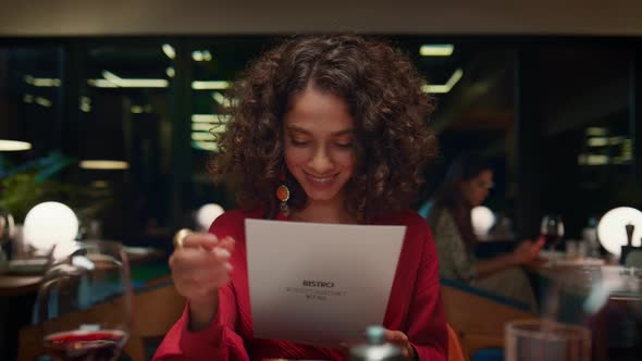 Pretty African American Woman Choosing Looking Menu at Fancy Restaurant Table alt