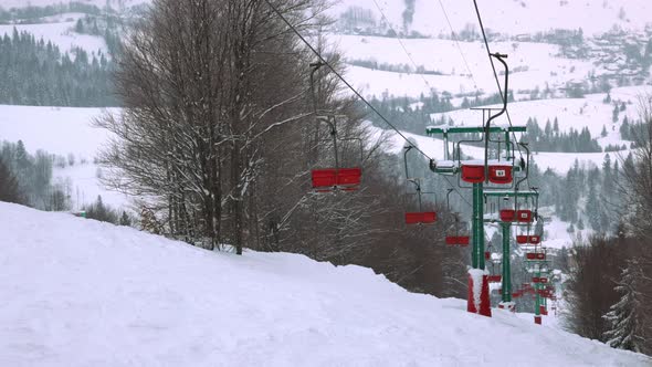 View of the Ski Lift Against the Background of a Mountain Forest and Gray Sky in the Carpathians alt