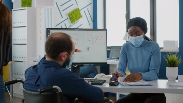 Handicapped Office Manager Explaining to Black Colleague Financial Startegy alt