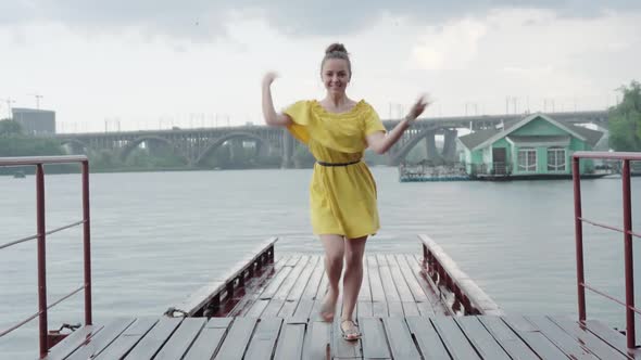 Cheerful Young Caucasian Girl Dancing on Pier Under Rain, Portrait of Positive Happy Woman in Yellow alt