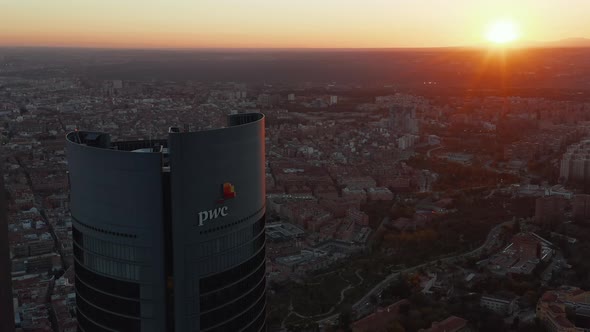Aerial View of Top of Tall Business Skyscraper with City and Sunset in Background alt