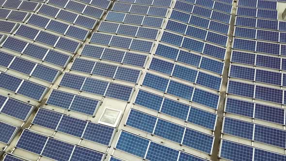 Aerial view of solar power plant with blue photovoltaic panels mounted of industrial building roof. alt