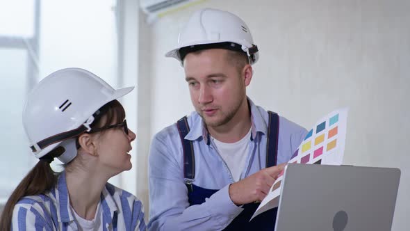 Portrait of Professional Workers Man and Woman in Protective Helmets and Color Sample in Their Hands alt