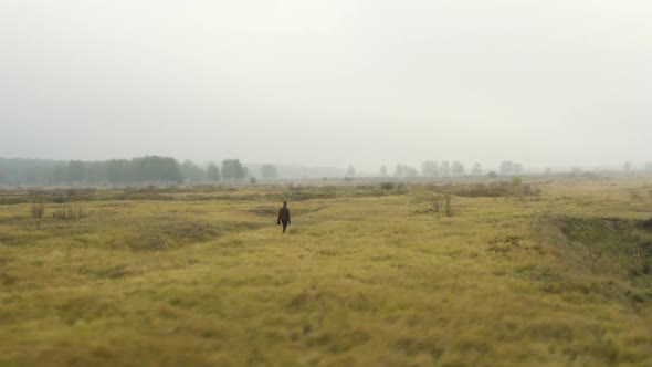 Documentarist standing in a foggy moorland, looking around, Czechia. alt