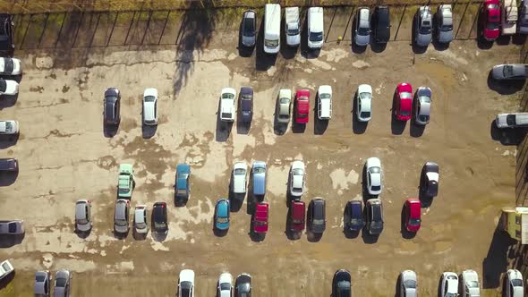 Top down aerial view of old parking lot with ruined dirty surface and many parked cars alt