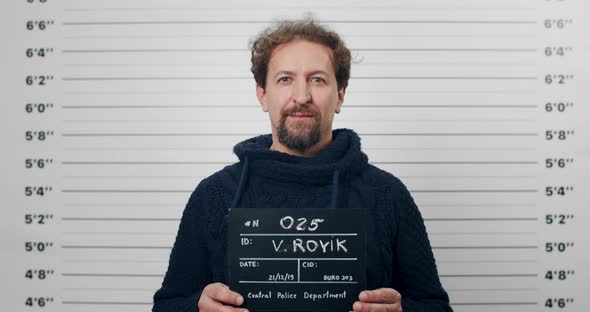 Portrait of Adult Bearded Man Holding Sign for Photo in Police Department alt