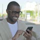African Man Browsing Internet on Smartphone Outdoor