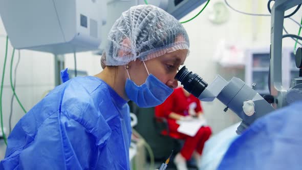 Surgeon looks to the microscope while providing operation in operation room. alt