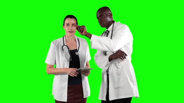 a Caucasian and African American people wearing a surgeon blouse and scrumbs in a green