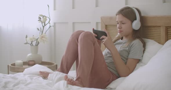 Child Girl Is Using Smartphone, Playing Game Online After Waking Up in Sunday Morning, Internet alt