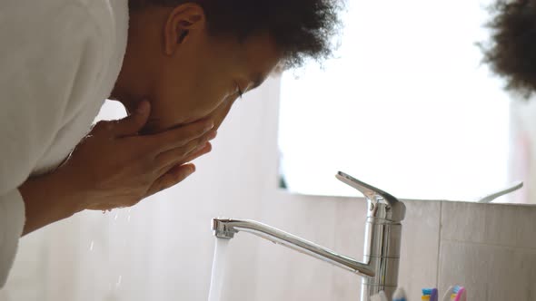 Close Up of African Man Washing Face in Bathroom Sink alt