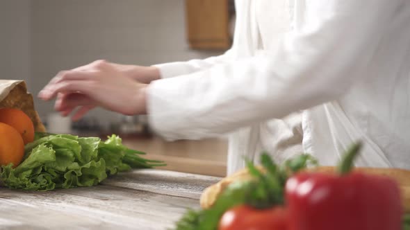 Hands Spread Vegetables From A Craft Paper Bag. Female Hands Place Vegetables On The Kitchen Table alt