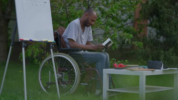 Side View Wide Shot Portrait of Desperate Depressed Disabled Man in Wheelchair Admiring Photo alt