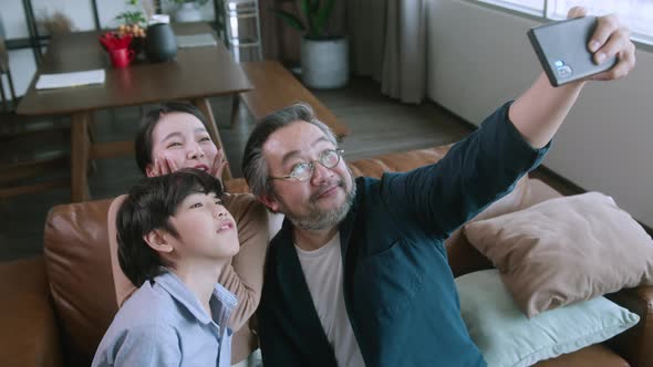 Asian family holiday activity dad holding smartphone taking a selfie photo together