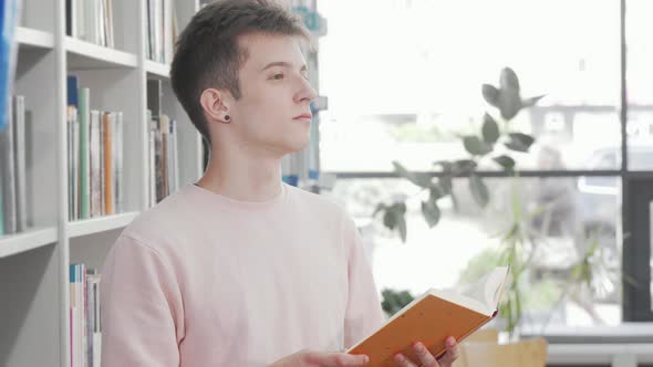 Young Man Enjoying Reading a Book at the Library