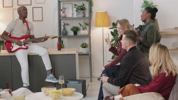 Young Black Man Playing Guitar for Group of Friends alt