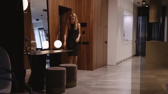 A Woman in Dress Returns Home After a Hard Day at Work Takes Off Her Shoes alt