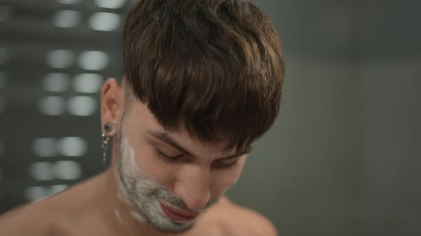 Closeup Young Man Removing Shaving Foam From Lips Standing Indoors in Bathroom alt