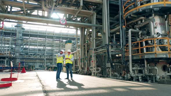 Refinery Engineers are Talking Among the Factory Pipes alt