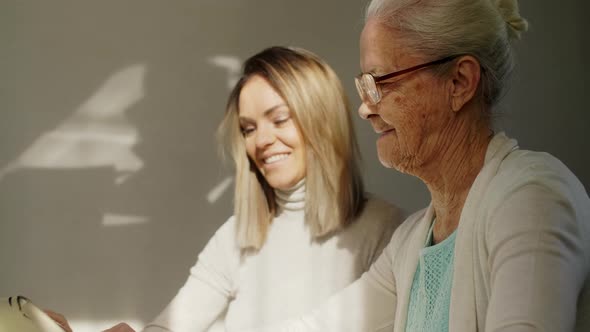 Female Volunteer Teaching Senior Woman to Use Tablet