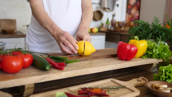 Pregnant Woman Cooking At Home, Cutting Lemon, Doing Fresh Green Salad. Healthy Pregnancy Concept alt