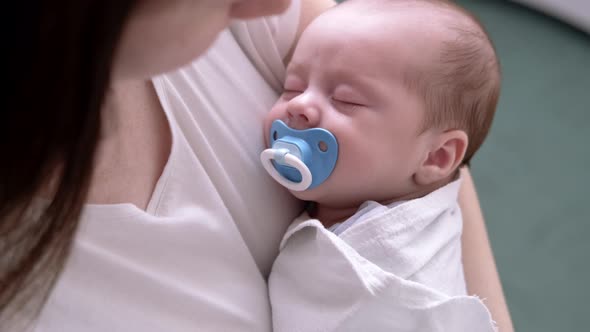 Little Newborn Baby Boy Sleeping with Baby Dummy on Mother Hands at Home Mom Puts Baby to Sleep alt