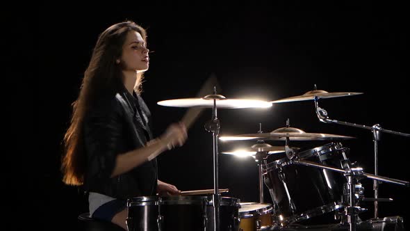 Girl Drummer with Chopsticks Beats Rhythmic Music. Black Background. Side View alt