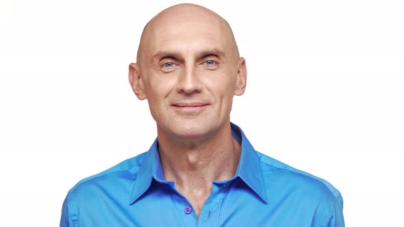 Middleaged Bold Caucasian Male in Blue Shirt Standing on White Background and Smiling alt