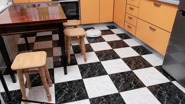 Robot Vacuum Cleaner Cleans in the Modern House on the Floor at Kitchen alt