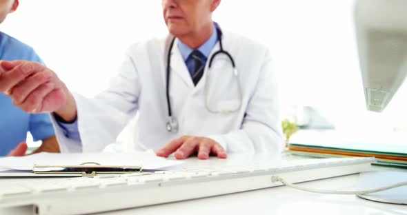Male doctor and coworker discussing over computer alt