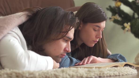 Sleepy Tired Guy and Girl Lying on the Floor and Read the Book alt