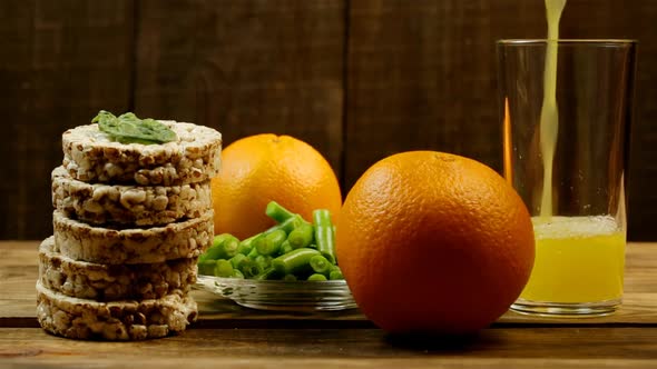 Oranges, Bread Rolls, Green Beans And Orange Juice Are Poured Into A Glass